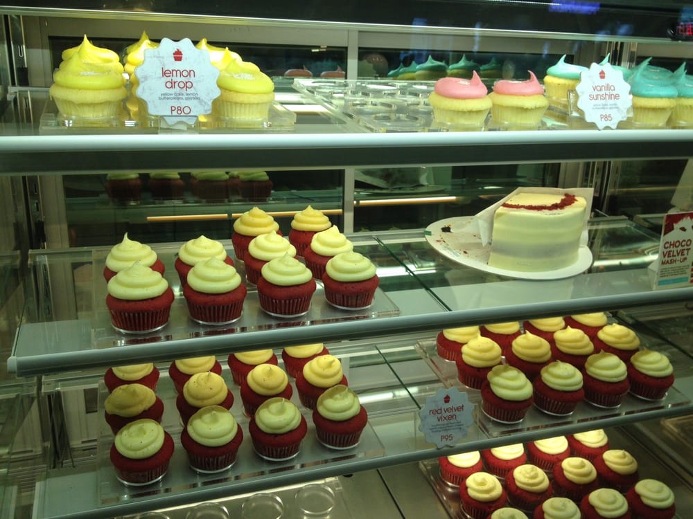 Red velvet cupcakes and lemon drop cupcakes with whole cake in display