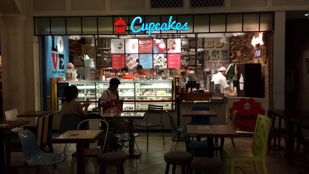 Cupcakes by Sonja storefront in mall with neon sign and display case